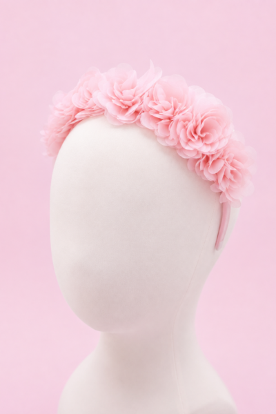 Baby pink floral hairband for girls featuring soft layered chiffon flowers on a comfortable fabric-covered headband, displayed on a white mannequin against a pastel pink background."